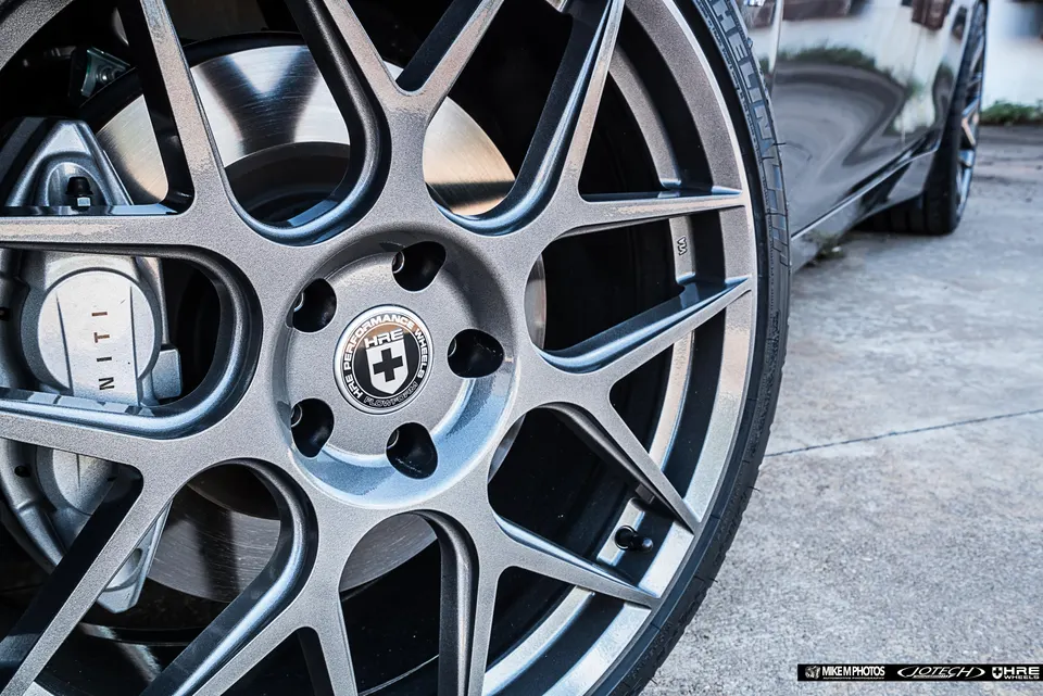 A close-up of an Infiniti car's HRE performance wheel, tire, and brake caliper.