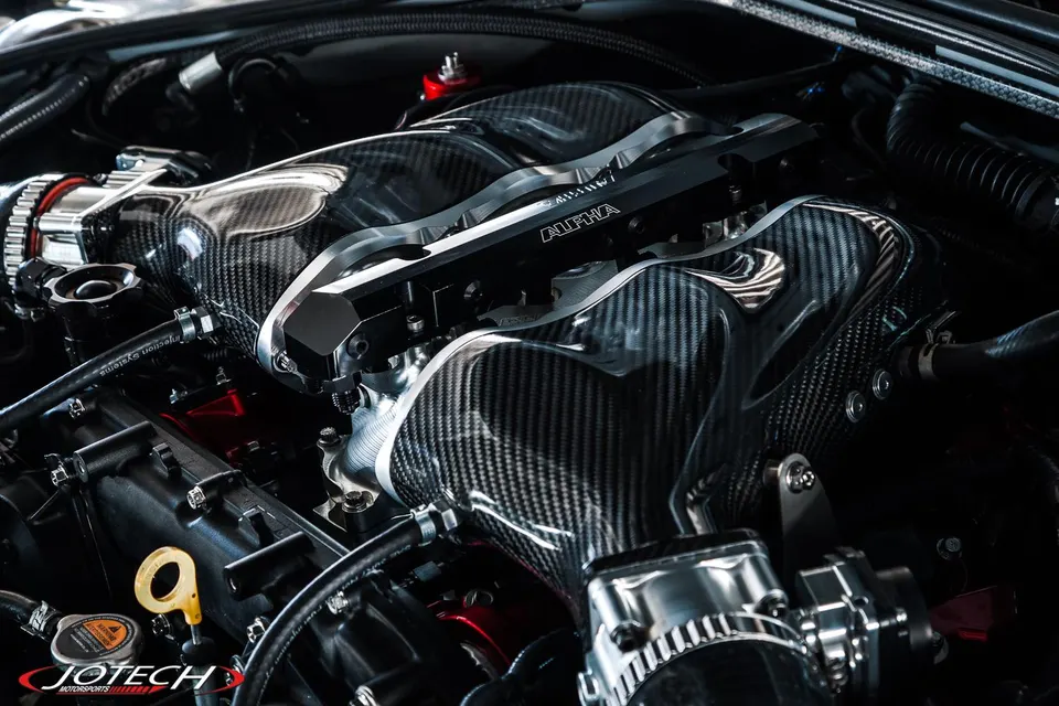 Close-up of a high-performance engine bay featuring a carbon fiber intake manifold and Alpha fuel rail.
