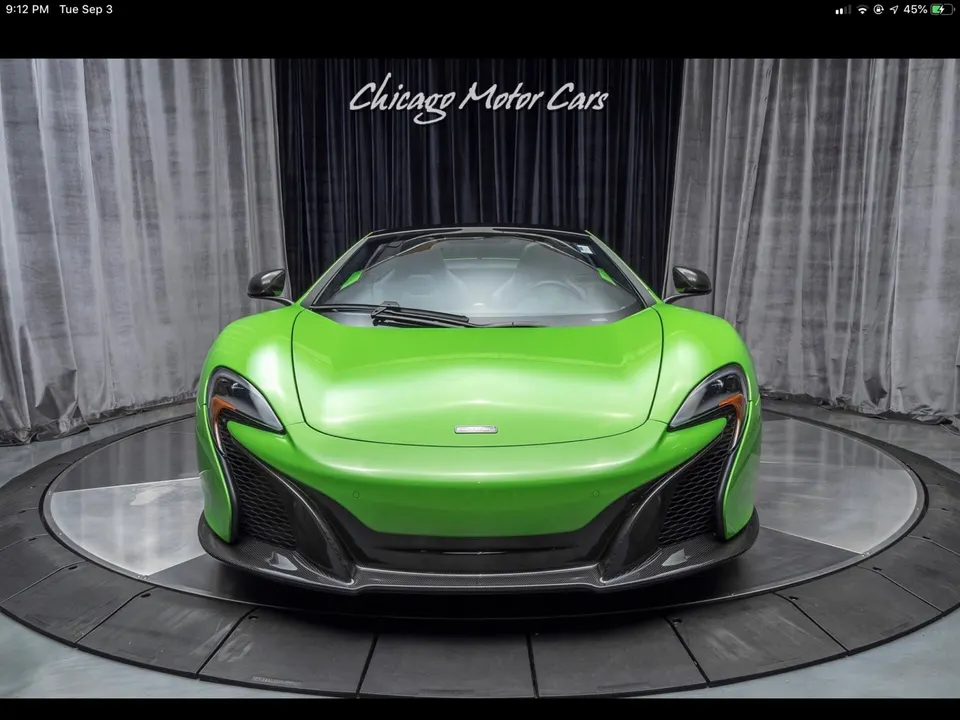 Green McLaren supercar front view in a professional studio setting with a black and grey backdrop