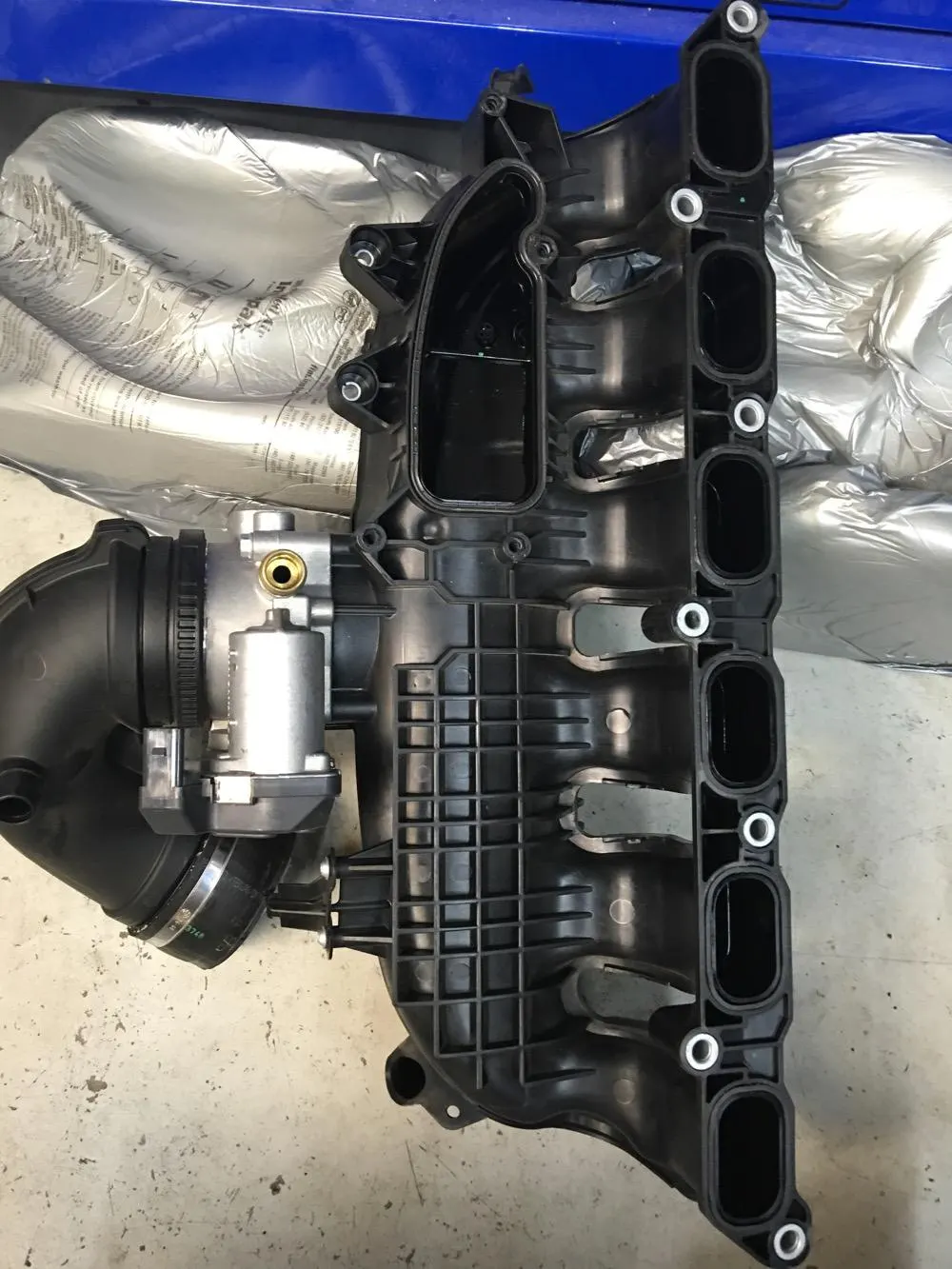 New intake manifold and throttle body for a performance build in a tuning shop.