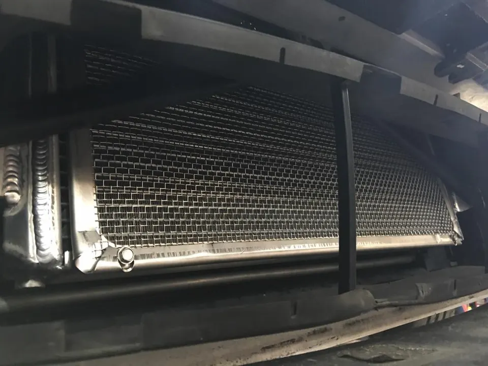 A close-up view of a large, aftermarket front-mount intercooler installed in a performance car.