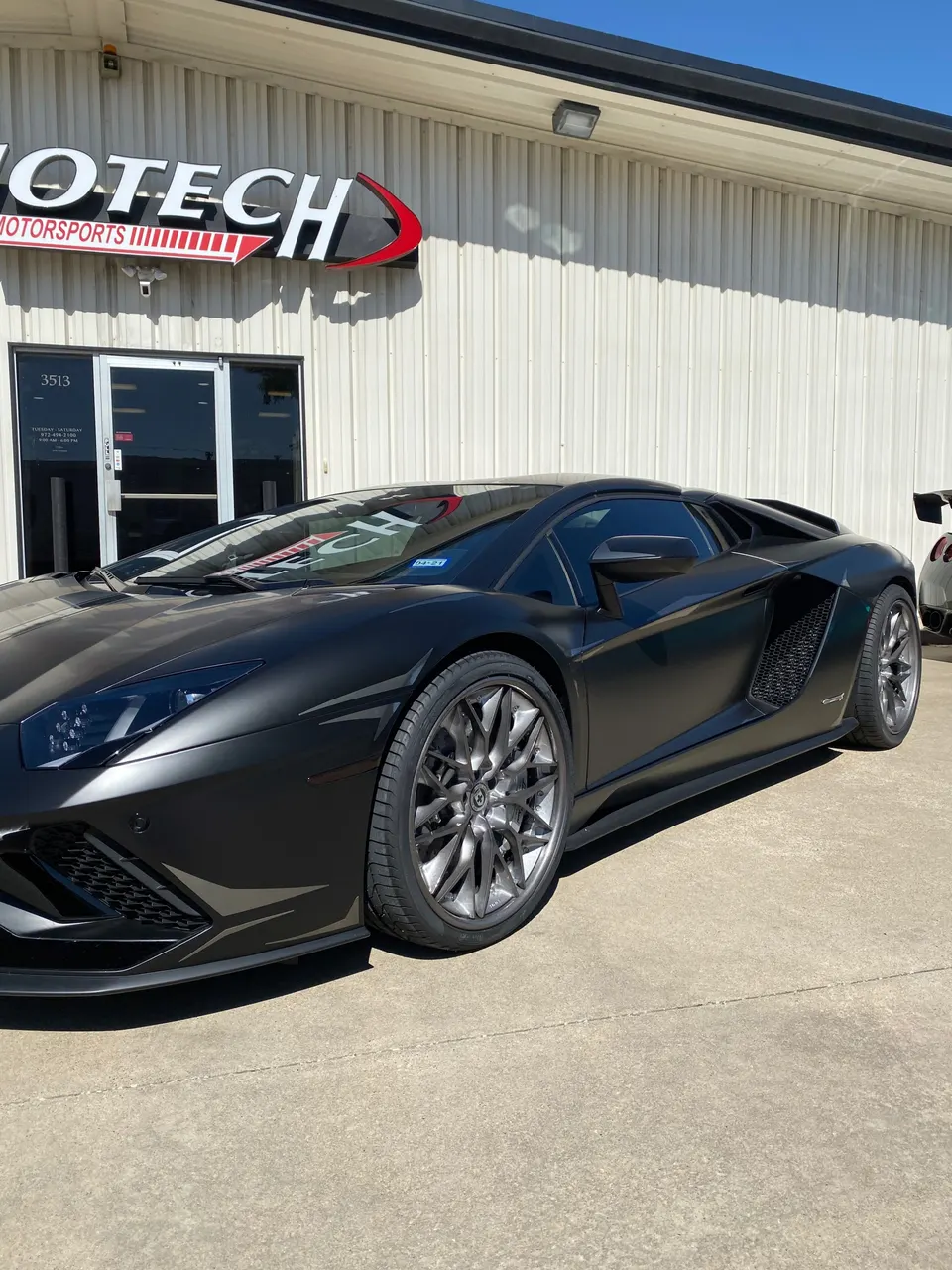 Matte black Lamborghini Aventador supercar parked outside Jotech Motorsports performance tuning shop.