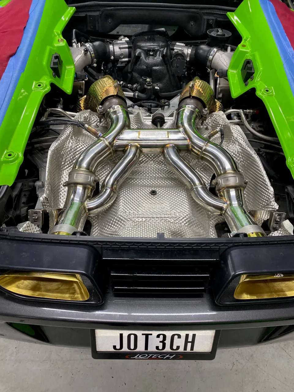 A close-up view of a Lamborghini Huracan's custom exhaust system and turbochargers in the engine bay.