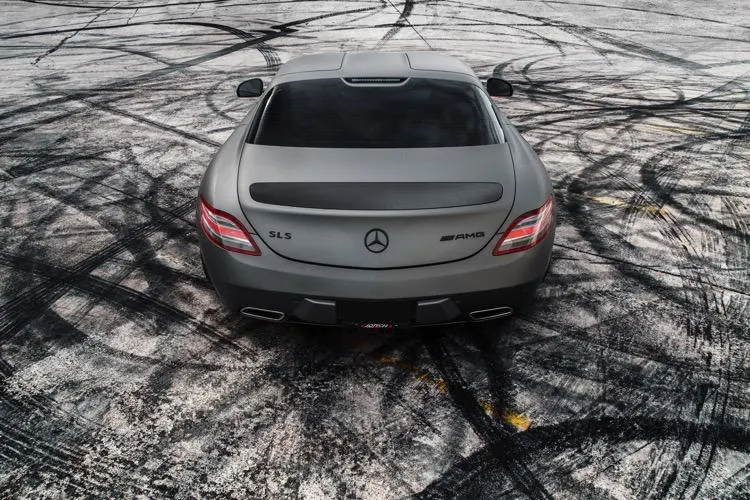 Matte grey Mercedes-Benz SLS AMG from above, showcasing its rear design on a ground covered with tire marks.