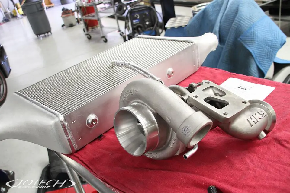 Garrett turbocharger and large intercooler on a red cloth in a Jotech Motorsports shop.