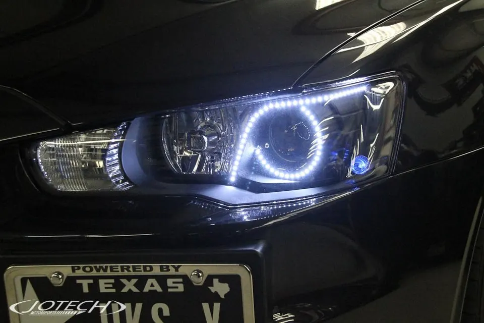 A close-up of a car's custom LED headlight with a unique light pattern and a Texas license plate.