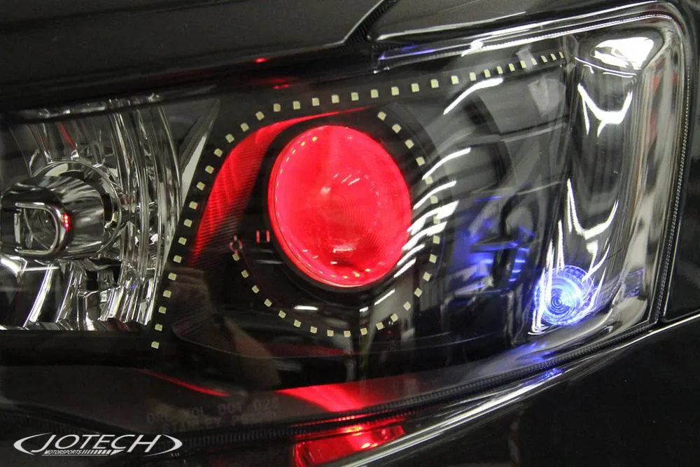 Close-up of a custom car headlight with red halo and blue accent lighting, featuring Jotech Motorsports branding.
