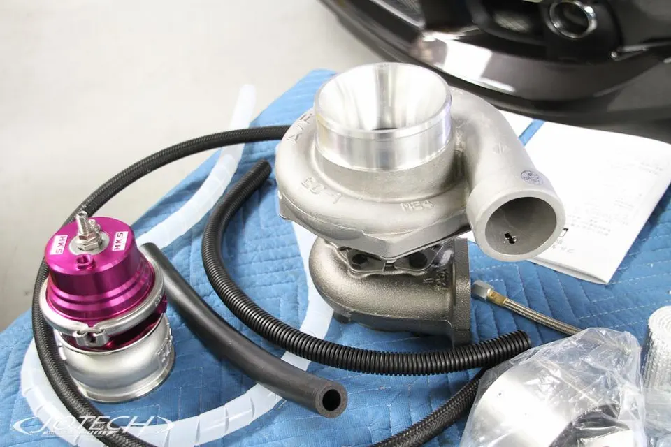 HKS blow-off valve and turbocharger kit laid out on a blue cloth, ready for installation in a performance shop.