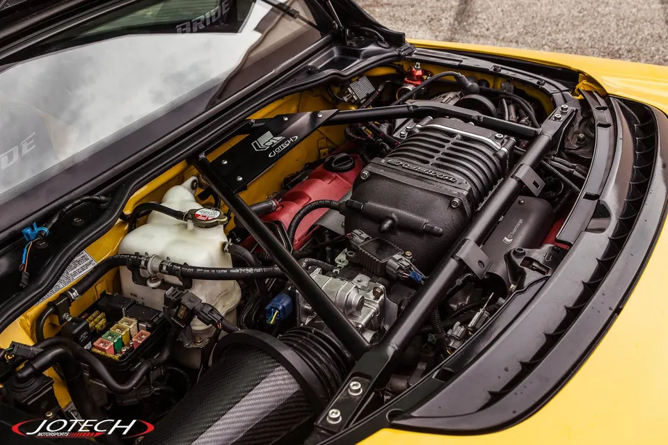 A close-up view of a supercharged Honda NSX engine bay featuring a prominent carbon fiber intake system.