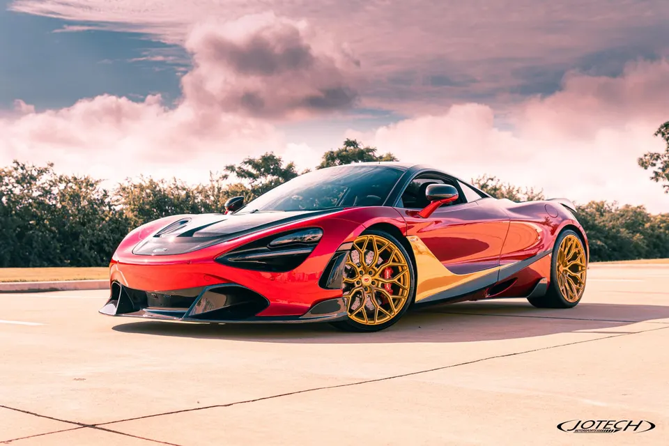 Red McLaren 720S supercar with custom gold multi-spoke wheels parked outdoors under a dramatic sky.