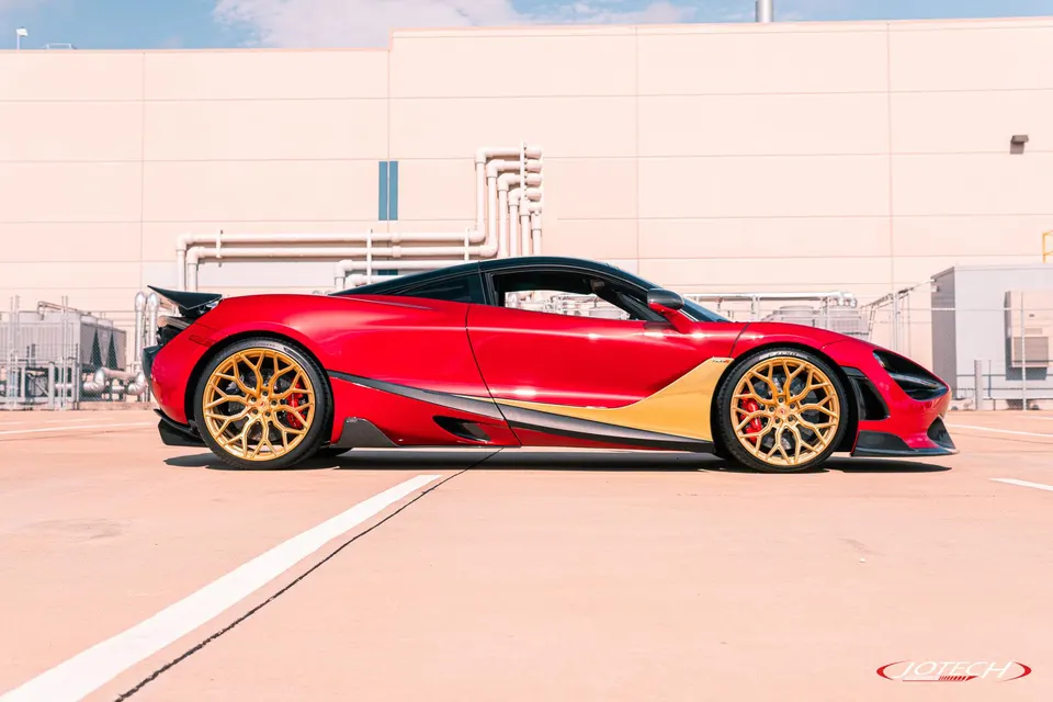 Red McLaren 720S with gold aftermarket wheels parked outdoors, showcasing its sleek side profile and custom modifications.