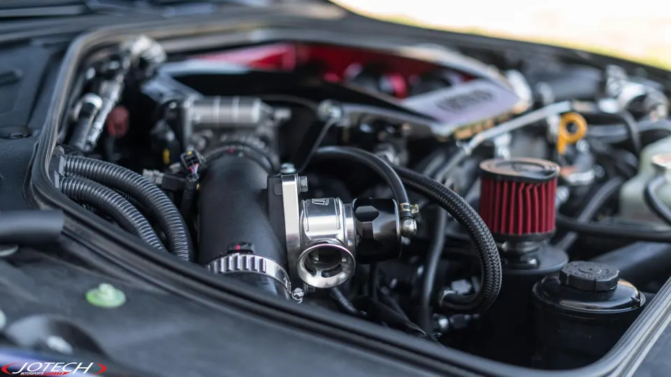 Close-up of a performance car engine bay showing a blow-off valve and aftermarket air filter.