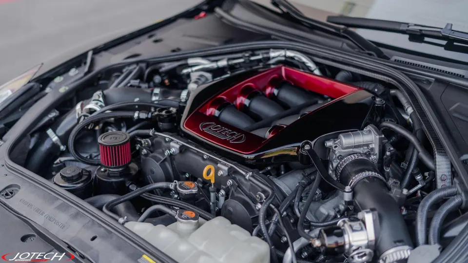 A detailed view of a Jotech Motorsports tuned engine bay, featuring a custom red intake manifold and performance air filter.