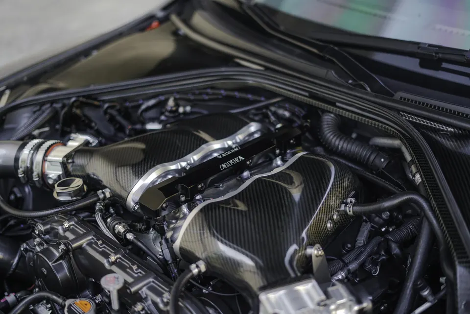 Close-up of a high-performance engine bay featuring a carbon fiber intake manifold and Alpha Performance components.