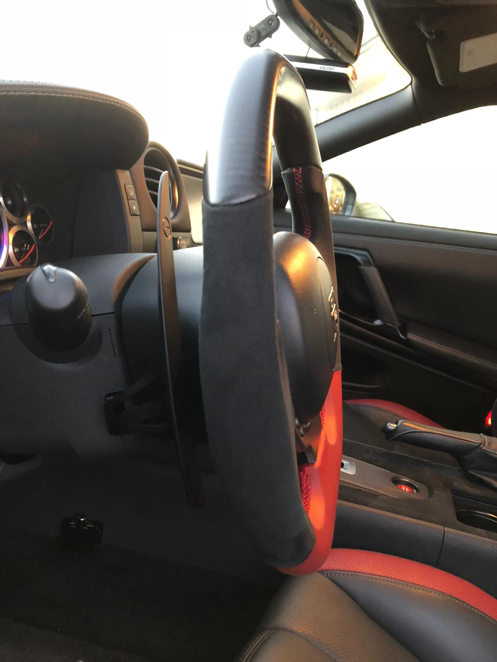 Close-up of a Nissan GT-R interior, showcasing the custom steering wheel with red accents and paddle shifters.