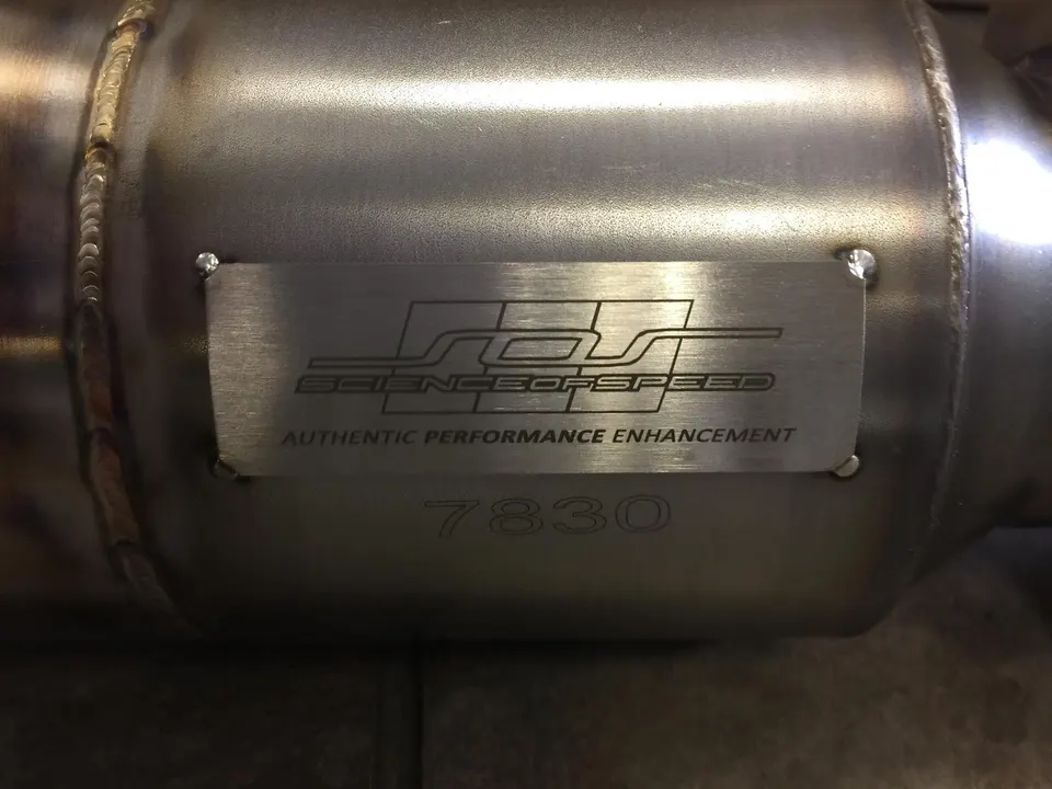 Close-up of a Science of Speed stainless steel exhaust component with visible welds and '7830' etched below the logo.
