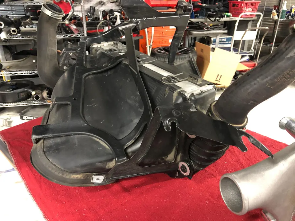 OEM airbox and intake piping on a workbench in a performance tuning shop.
