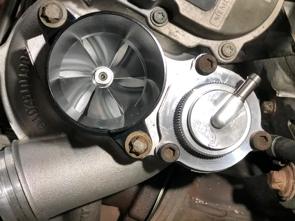 Close-up view of a turbocharger compressor wheel and a Forge blow-off valve in an engine bay.
