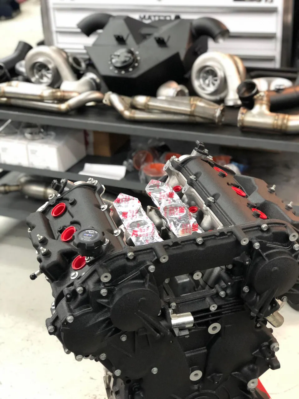 Built engine block with performance turbochargers and exhaust manifolds displayed in a Jotech Motorsports shop.