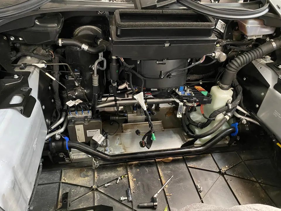 McLaren engine bay with air intake system and various components during a shop service or upgrade.