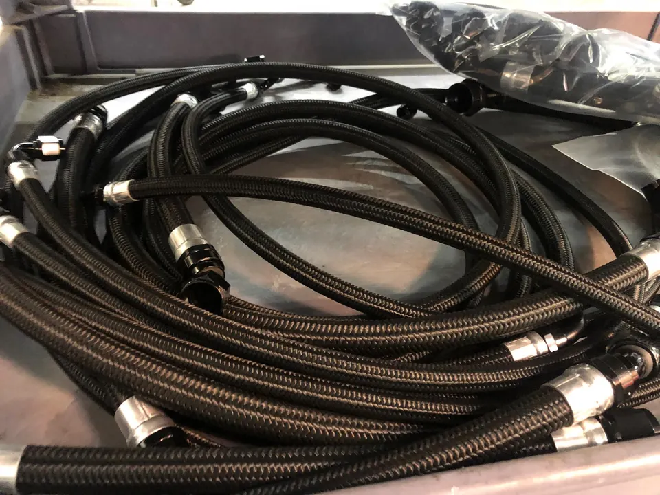 Close-up of new braided fuel lines with AN fittings ready for installation in a performance vehicle.