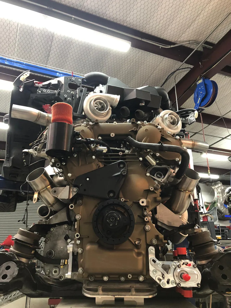 A high-performance engine with twin turbochargers and custom piping being assembled in a workshop.