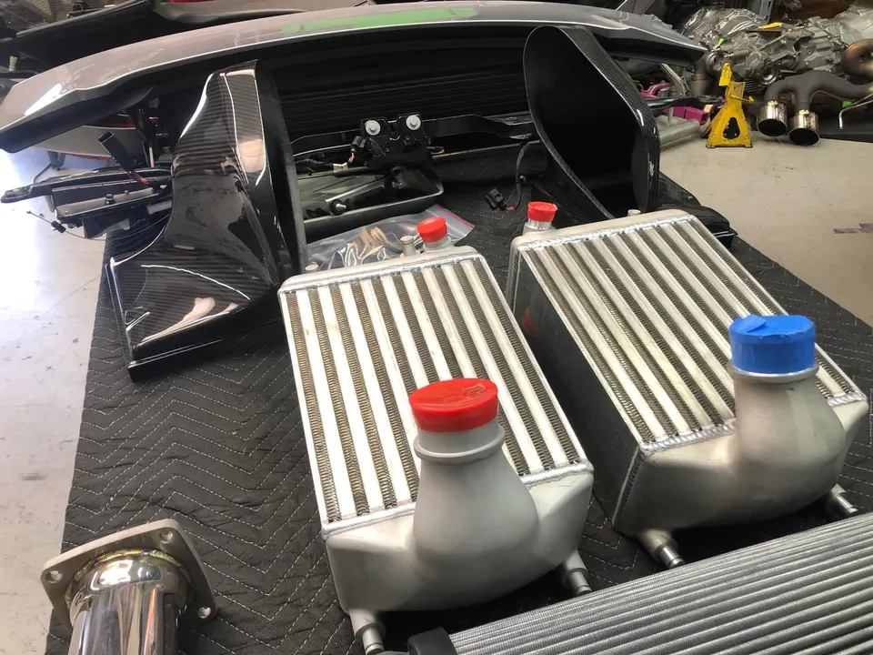 Aftermarket intercoolers and carbon fiber components laid out on a workbench in a performance tuning shop.