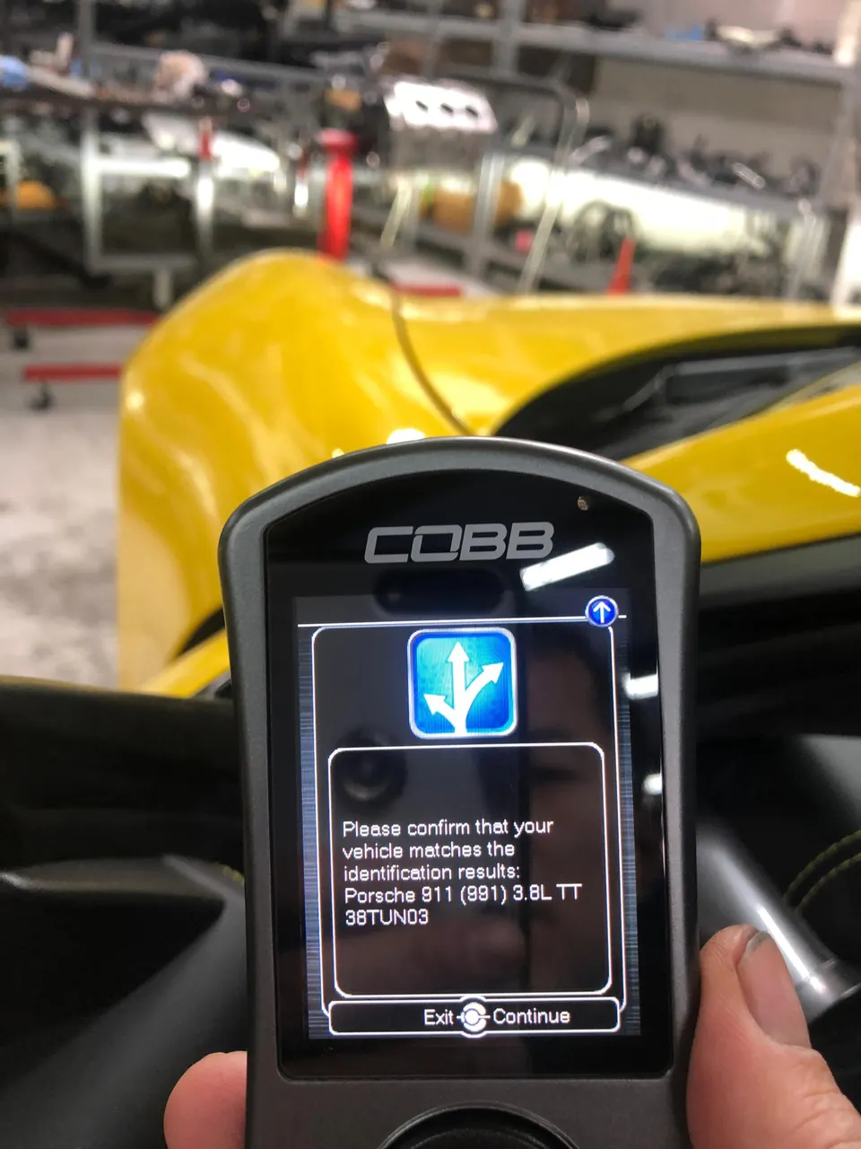 A Cobb Accessport tuning device displaying vehicle identification for a Porsche 911 (991) 3.8L TT in a shop setting.