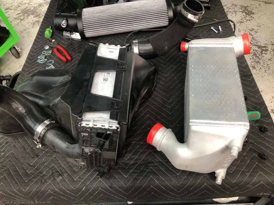 Aftermarket intercooler and air intake system laid out on a shop mat, ready for installation.