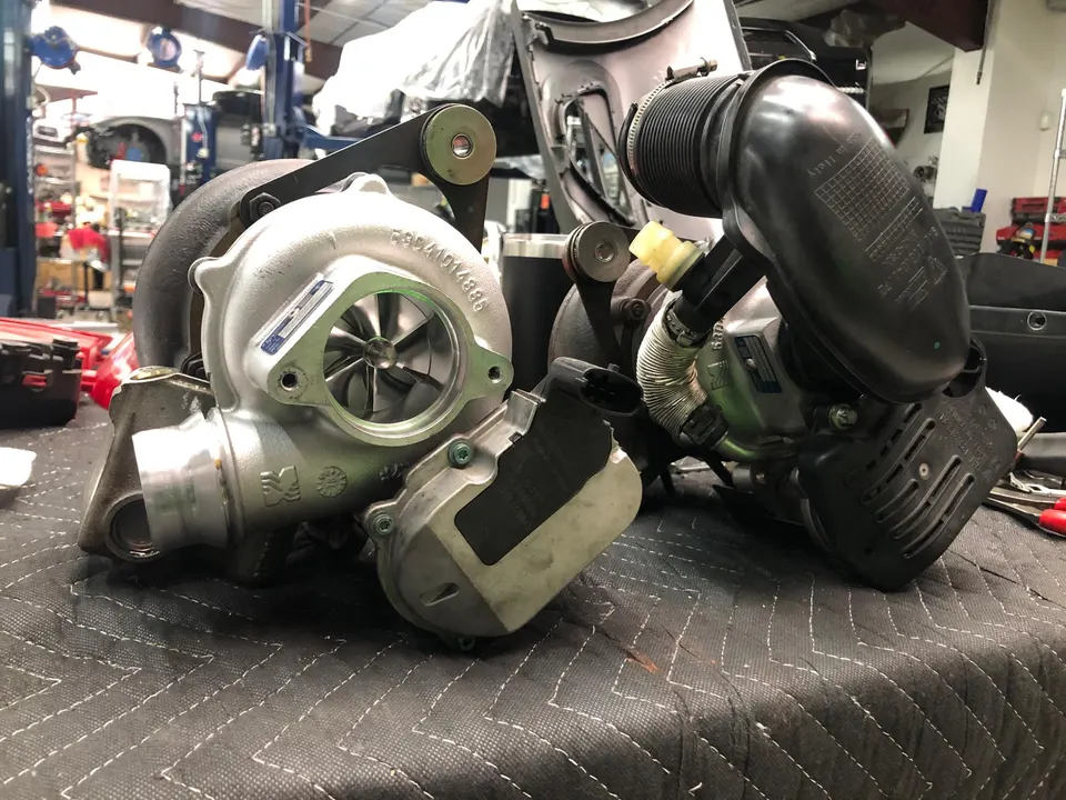 Two turbochargers and air intake components on a workbench in a performance tuning shop.