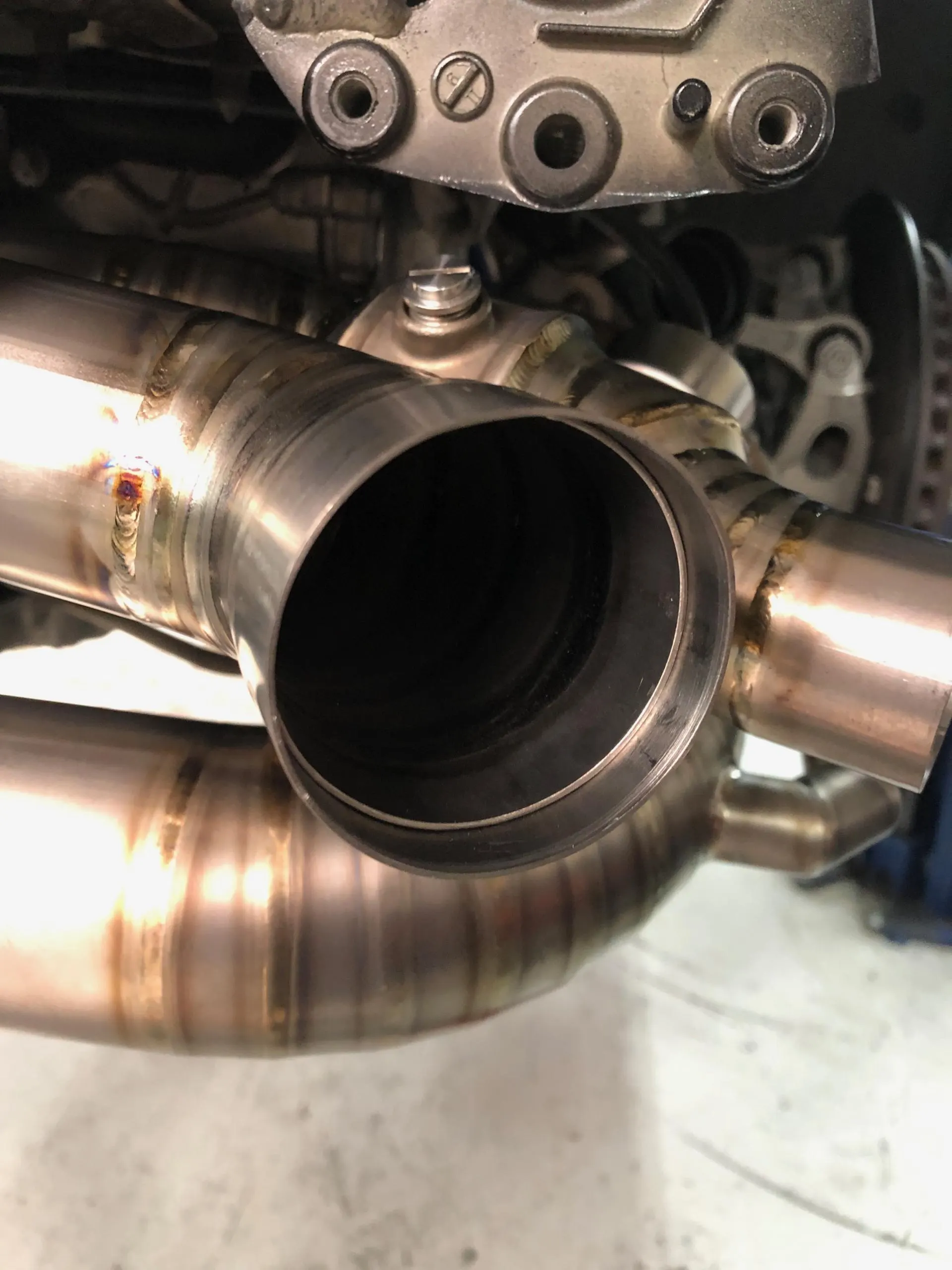 Close-up of a custom stainless steel exhaust pipe with visible welds, likely part of a performance exhaust system.
