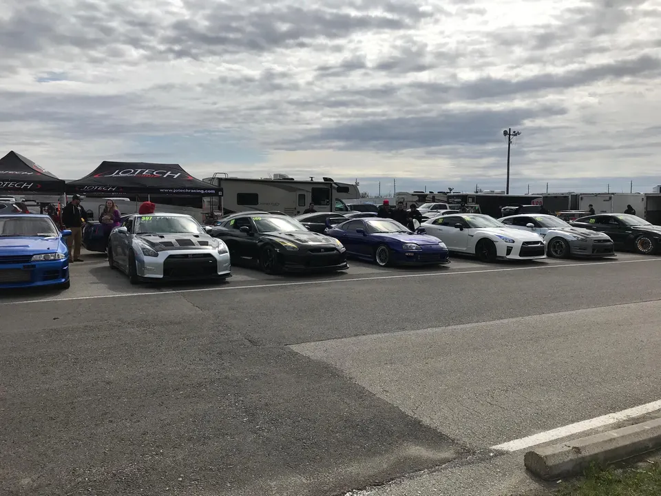 A line of modified Nissan GT-Rs, a Toyota Supra, and a Nissan Skyline R32 parked at a Jotech Racing event.