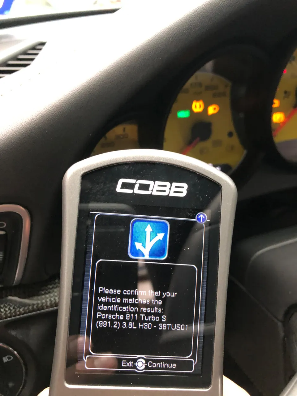 A COBB Accessport tuning device displaying vehicle identification for a Porsche 911 Turbo S (991.2) inside the car.