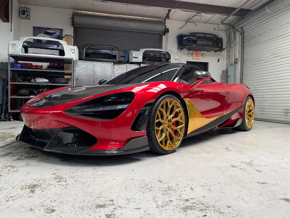 Red McLaren 720S with custom gold wheels and carbon fiber aero parked in a performance shop.