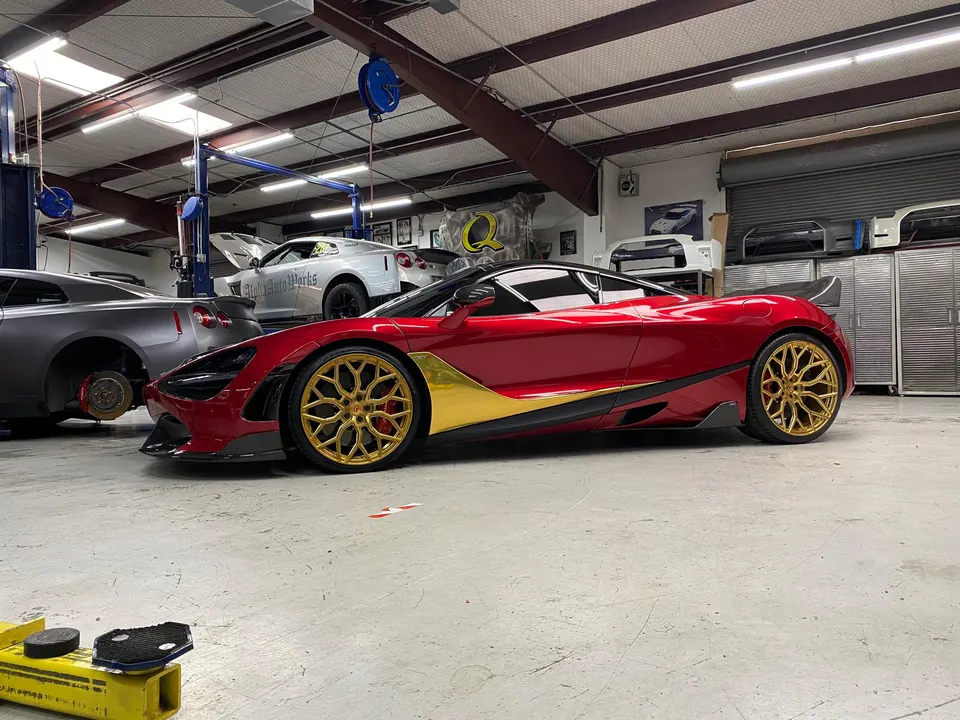 Red McLaren with gold wheels and two Nissan GT-Rs in a performance tuning shop with car lifts and parts.