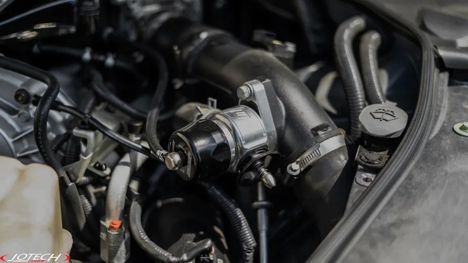 A close-up view of an aftermarket blow-off valve and boost piping in a performance car's engine bay.