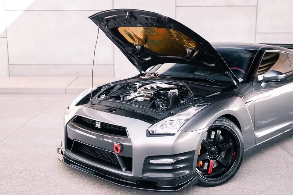 A silver Nissan GT-R with its hood open, showcasing the engine bay and custom front splitter.
