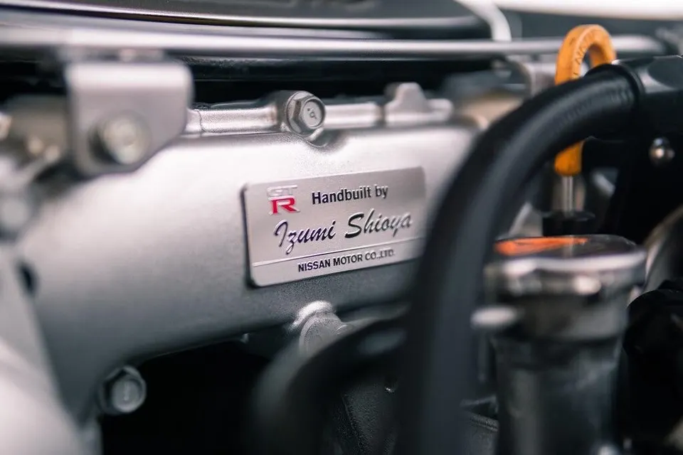 Close-up of a Nissan GT-R engine plaque, handbuilt by Izumi Shioya, showcasing engine detail.