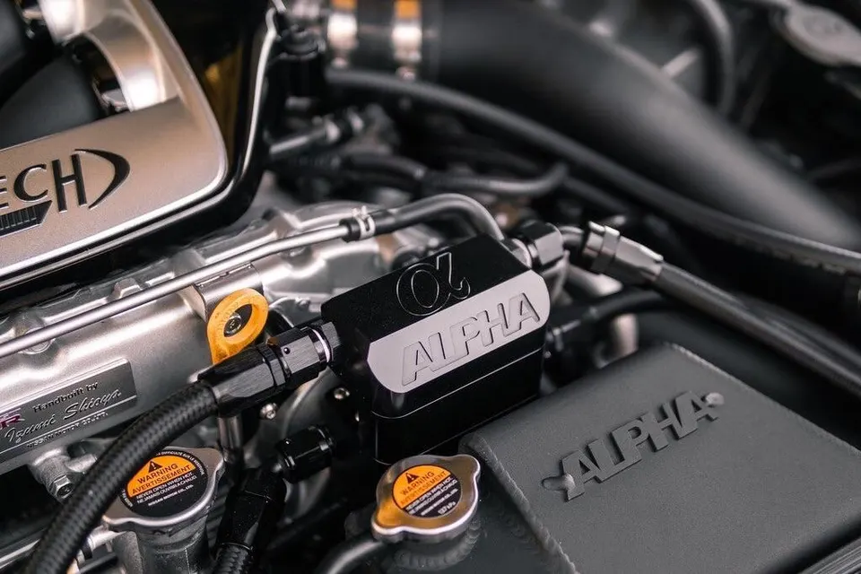 Close-up of a performance engine bay featuring Alpha Performance intake system and oil catch can