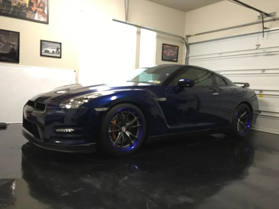 Blue Nissan GT-R with custom wheels and orange brake calipers parked in a clean garage.