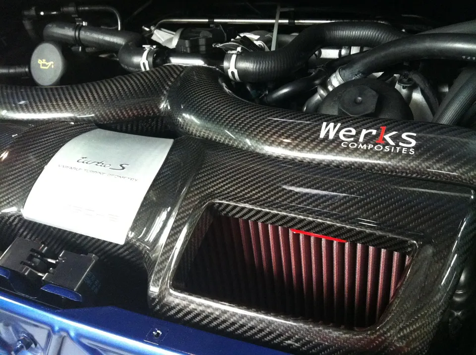Close-up of a Porsche Turbo S engine bay featuring a Werks Composites carbon fiber induction system with a visible air filter.