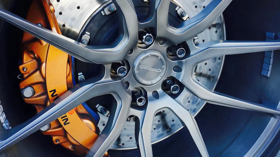 Close-up of a Jotech wheel with an orange Nissan brake caliper and slotted rotor on a performance car.