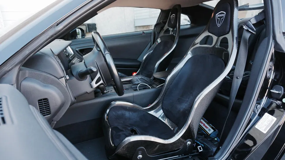 Custom carbon fiber racing seats and steering wheel in a Nissan GT-R interior.