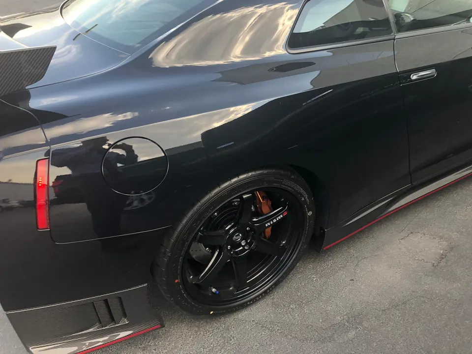 Black Nissan GT-R with Nismo wheels, Brembo brakes, and carbon fiber exterior aero including side skirts and rear diffuser.