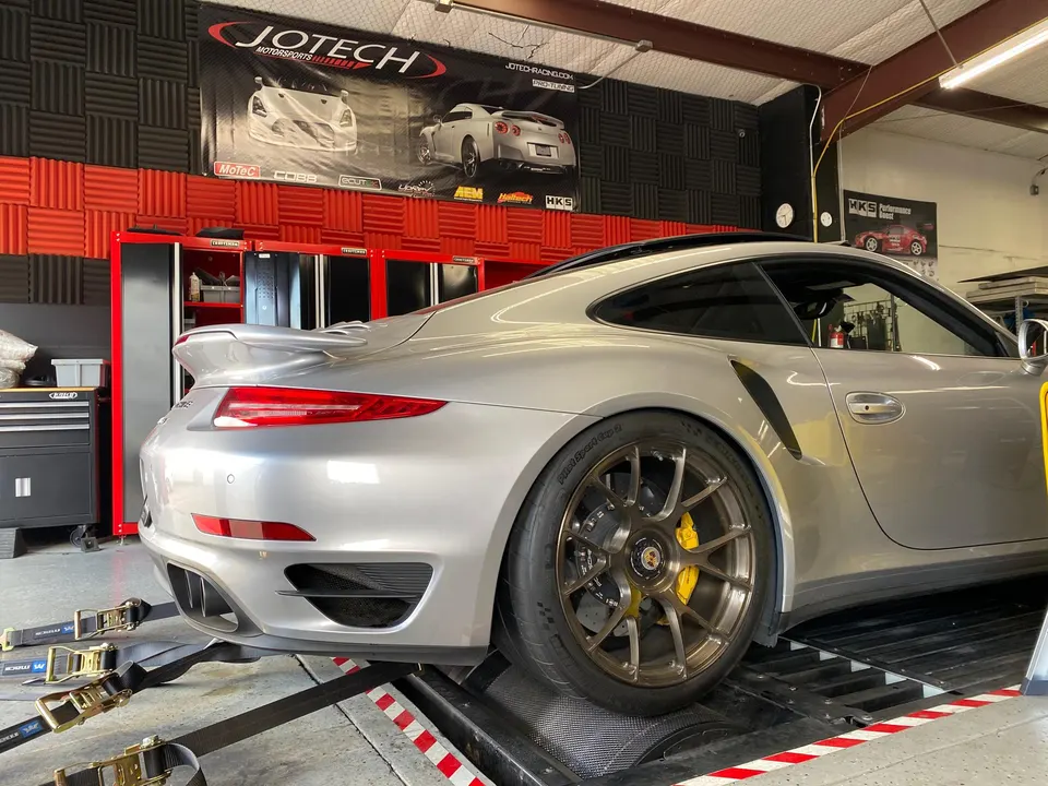 Silver Porsche 911 Turbo S strapped to a dynamometer at a performance tuning shop