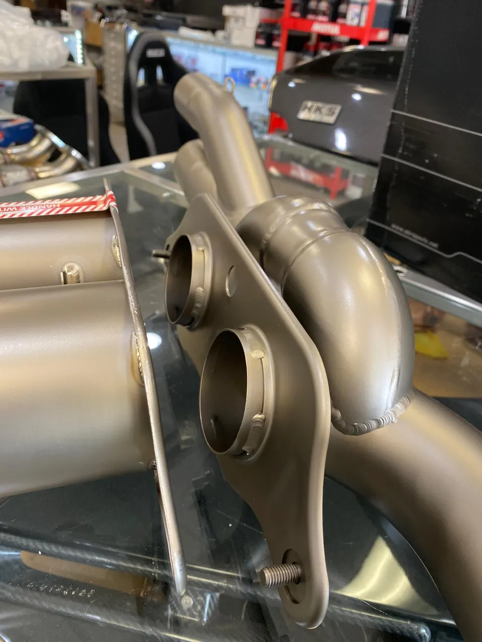 Close-up of titanium exhaust components with visible welds on display in a performance shop.