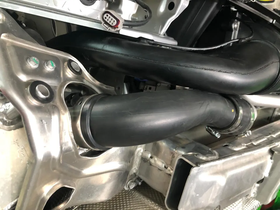 Close-up view of black boost pipes and metal brackets in a car's engine bay or undercarriage.