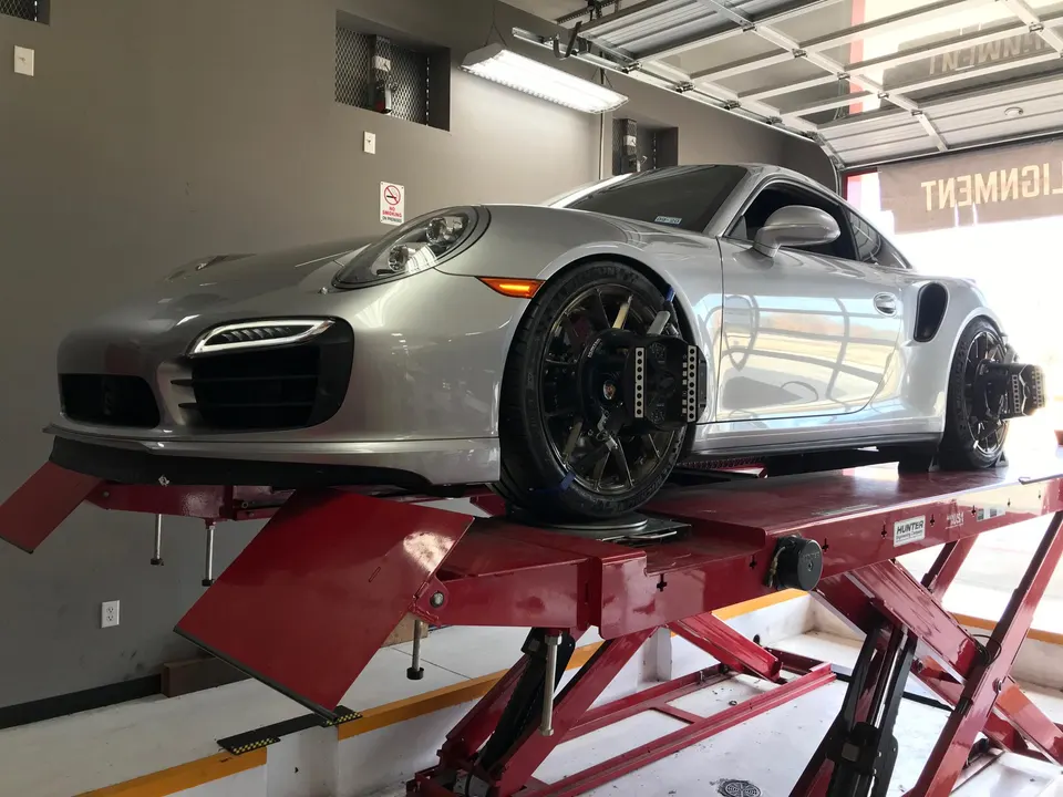 Silver Porsche 911 on a Hunter alignment rack in a performance tuning shop.