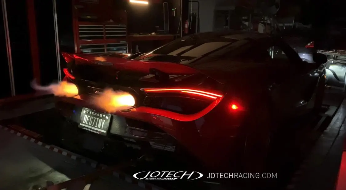 Red McLaren 720S on a dyno with flames shooting from the exhaust during a tuning session at Jotech Motorsports