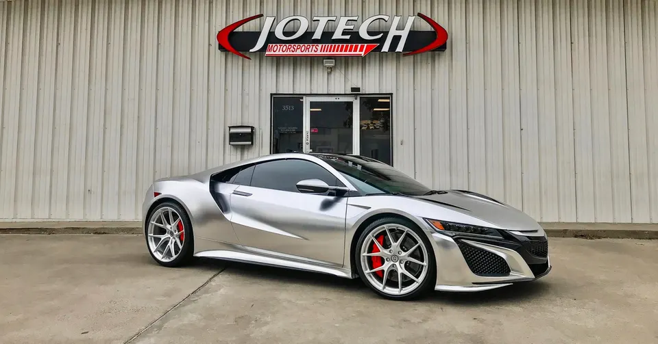 Silver Acura NSX with custom wheels and red calipers parked in front of Jotech Motorsports performance shop.